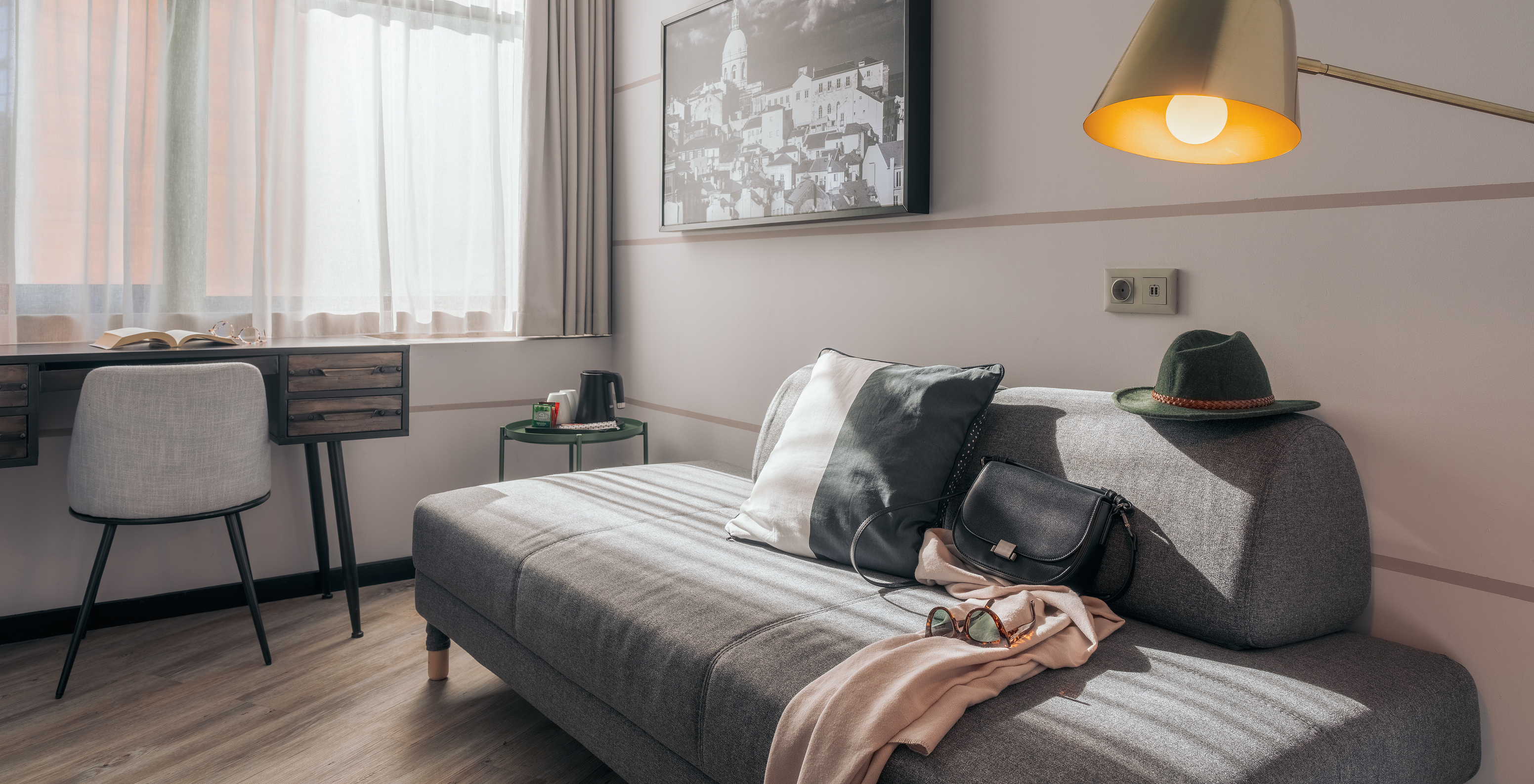 Le Double Supérieur du Pestana Lisboa Vintage a un canapé gris une bureau avec chaise une table d'appoint et un tableau