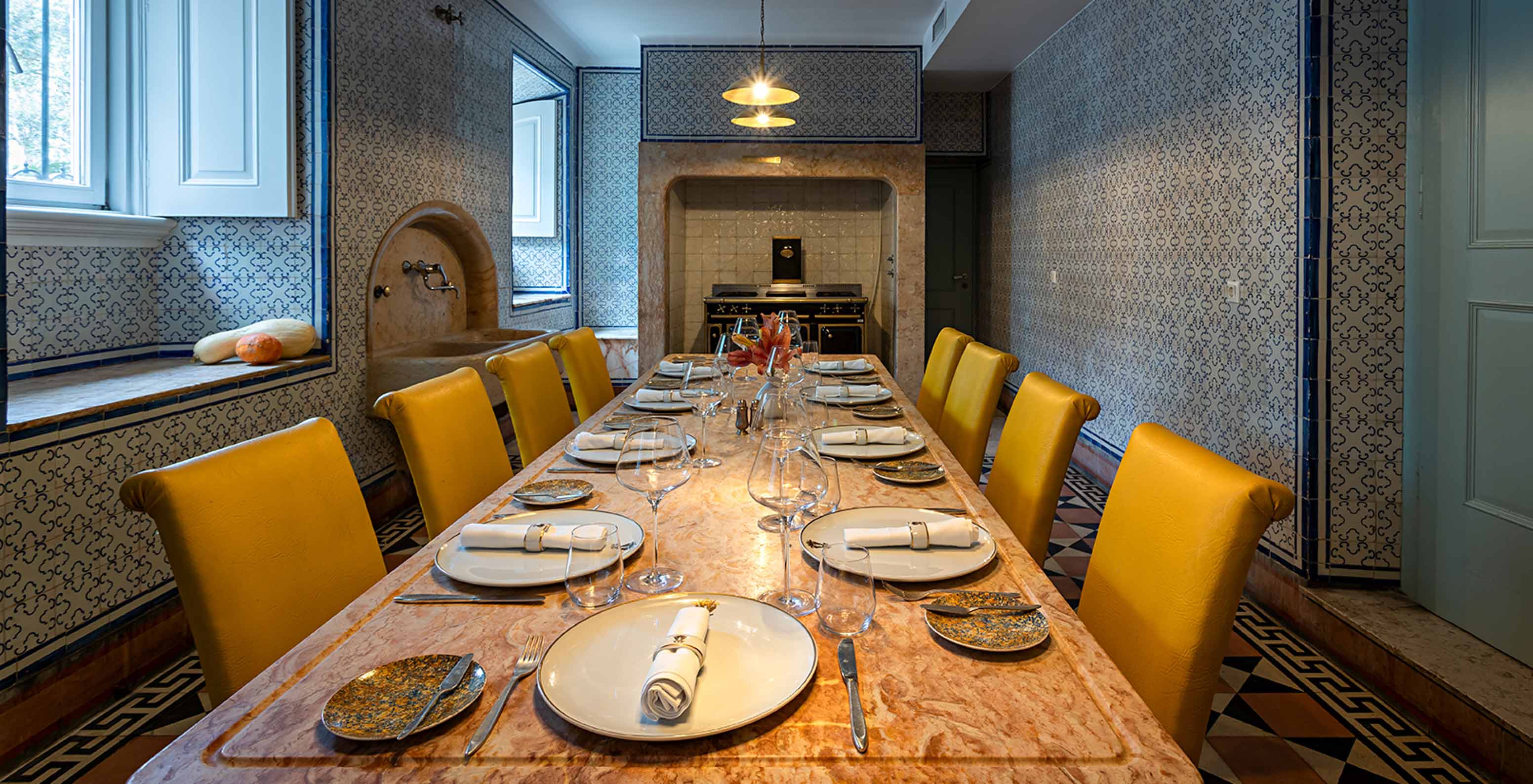 Le Pestana Palace possède une ancienne cuisine pour des événements privés, avec une table en pierre et des chaises jaunes