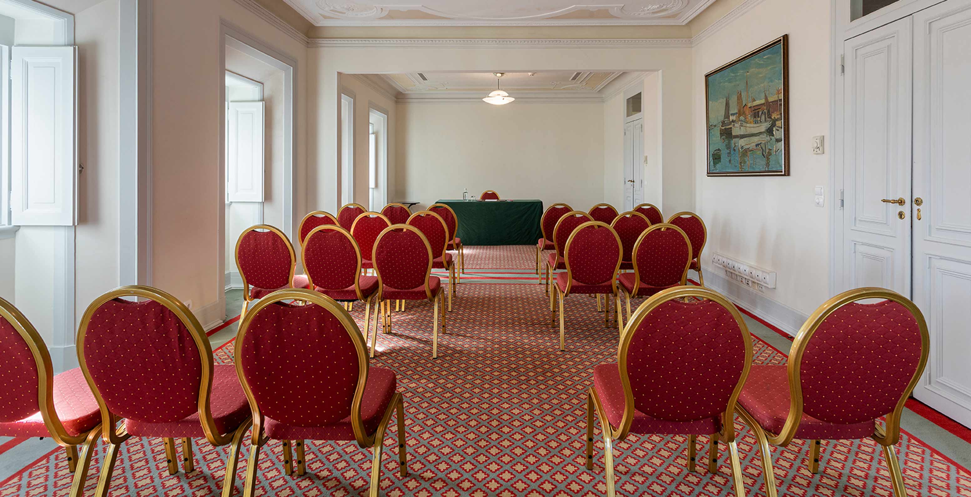 Le Pestana Palace Lisboa a une salle de réunion avec plusieurs chaises rouges et une table verte rectangulaire