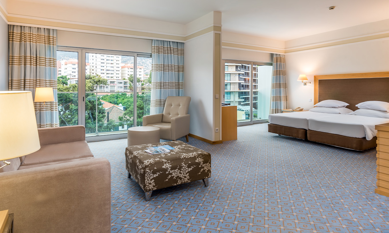 Le Double Familial du Pestana Carlton Madeira a un coin salon avec des canapés, un lit double et deux balcons