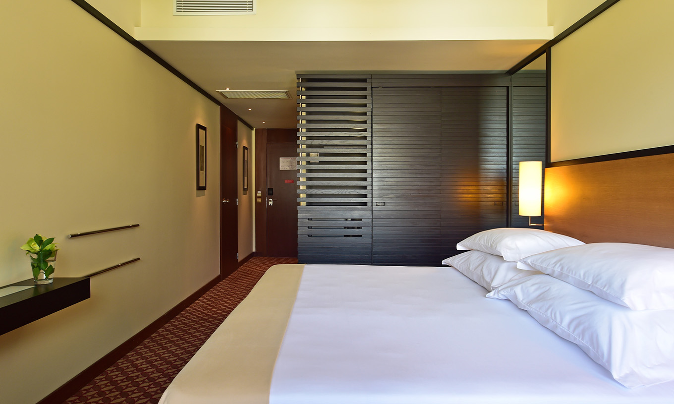 Le Classique Vue Jardin du Pestana Casino Park a un lit double avec une armoire en bois sombre et une lampe à côté