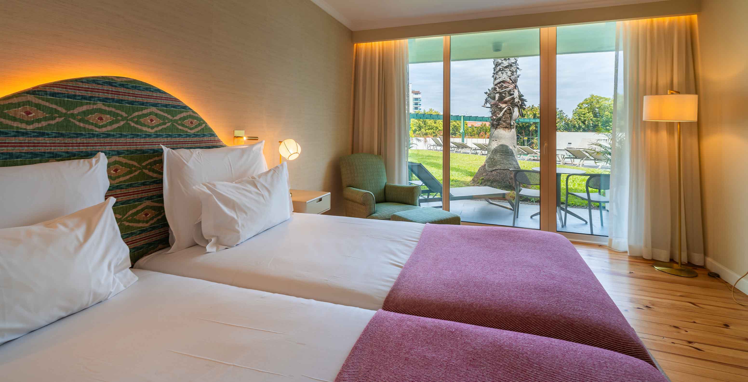 La Chambre Vue Piscine du Pestana Quinta Perestrello dispose d’un lit double avec une couette rose et d’un balcon avec vue