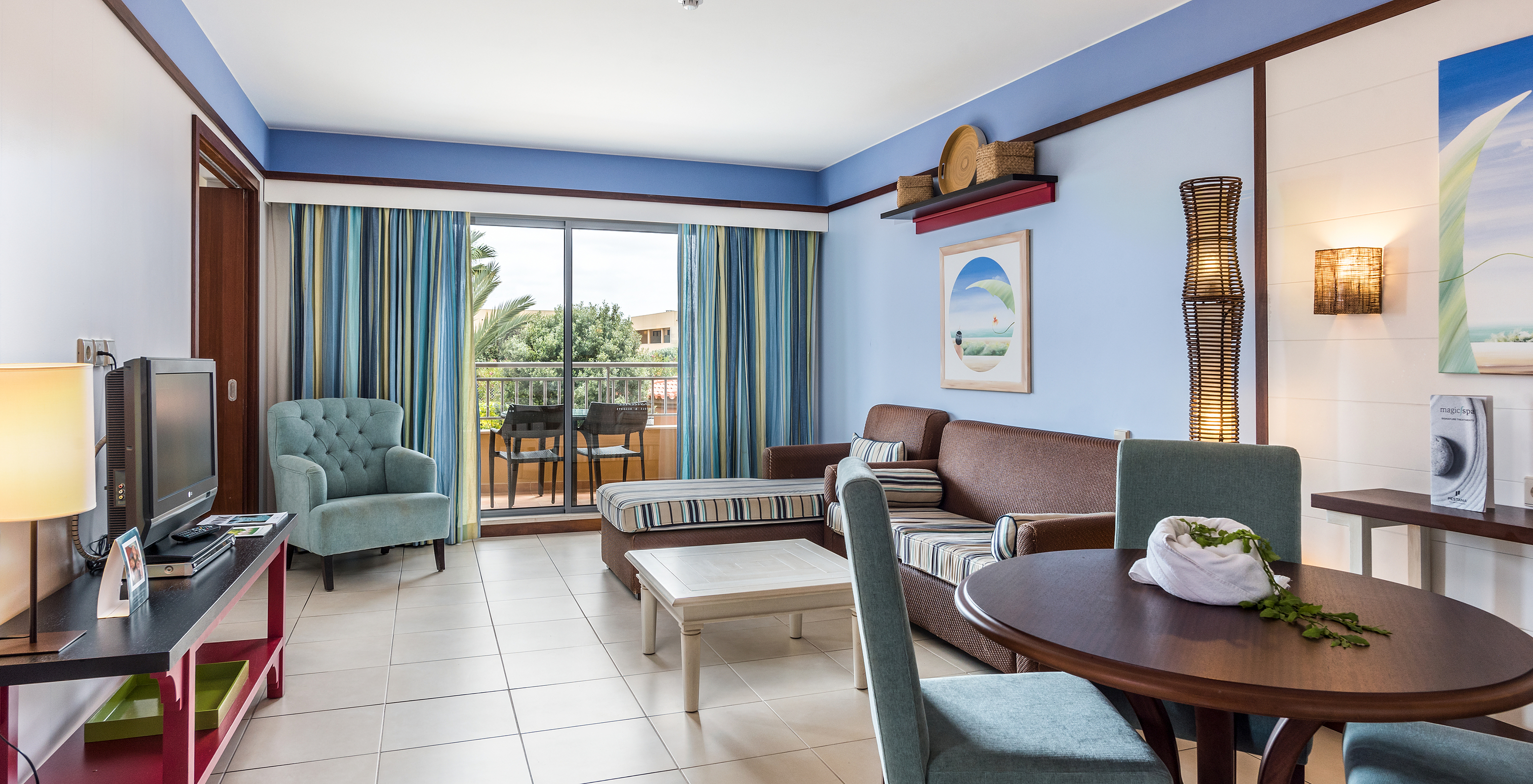 La Suite Appartement T2 du Pestana Porto Santo All Inclusive a un salon avec deux canapés, télévision et accès au balcon