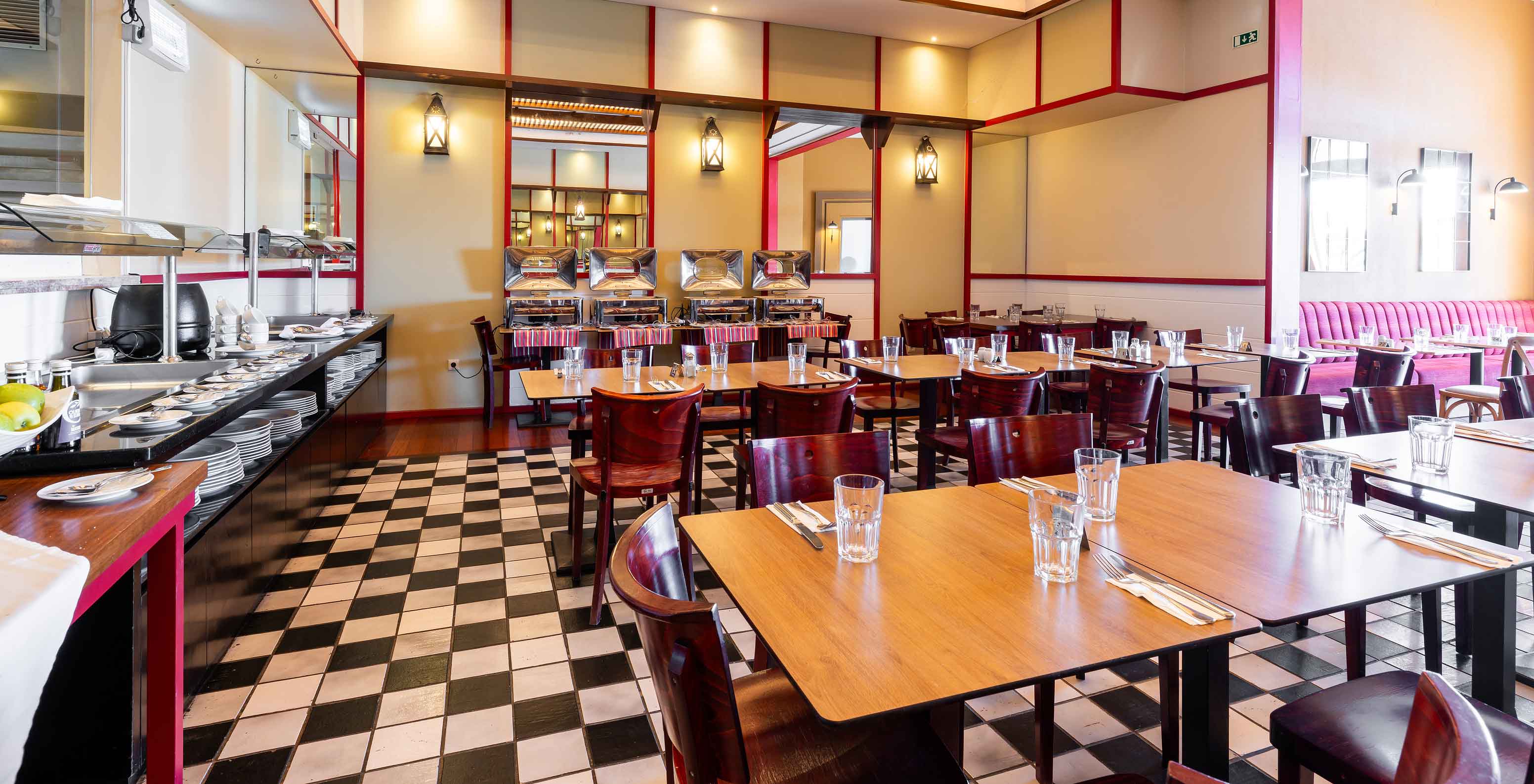 Le restaurant Luigi du Resort 5 étoiles à Porto Santo a un sol en carreaux noirs et blancs et des chaises sombres.