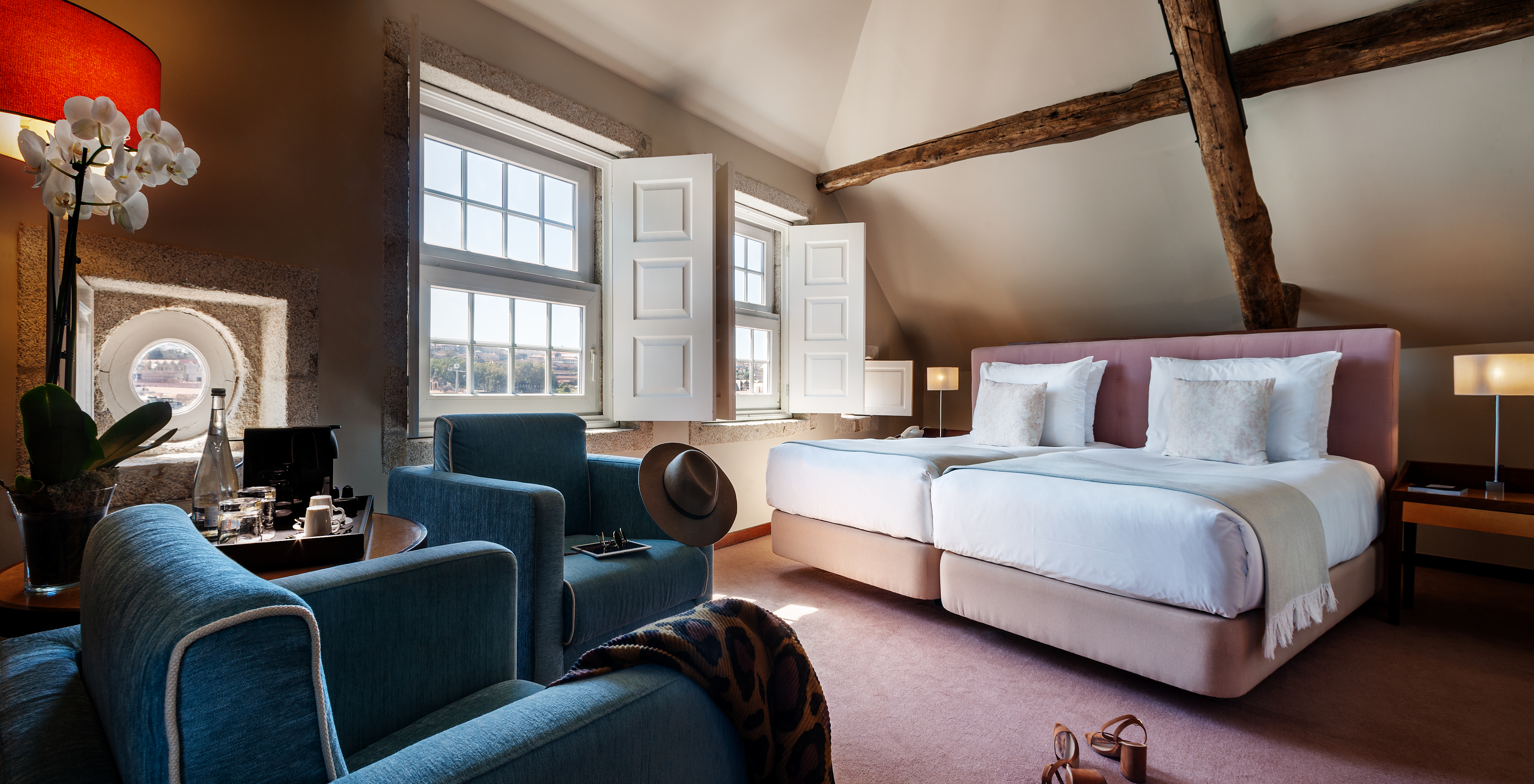 Le Plaza du Pestana Vintage Porto a deux lits, deux fauteuils, un tronc en bois au plafond et deux grandes fenêtres