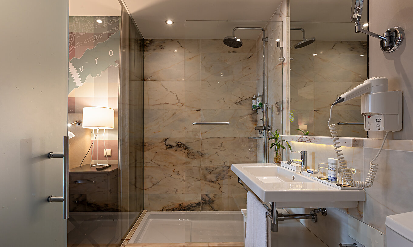 La Classic du Pestana Vintage Porto dispose d'une salle de bain avec un lavabo et une douche entourée de murs en marbre