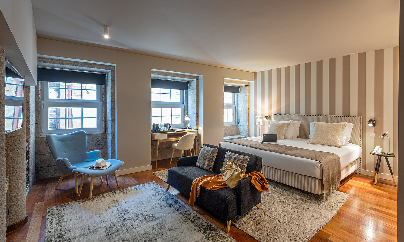 La Heritage Suite du Pestana Vintage Porto dispose d'un lit double, de deux canapés sur des tapis et de plusieurs fenêtres