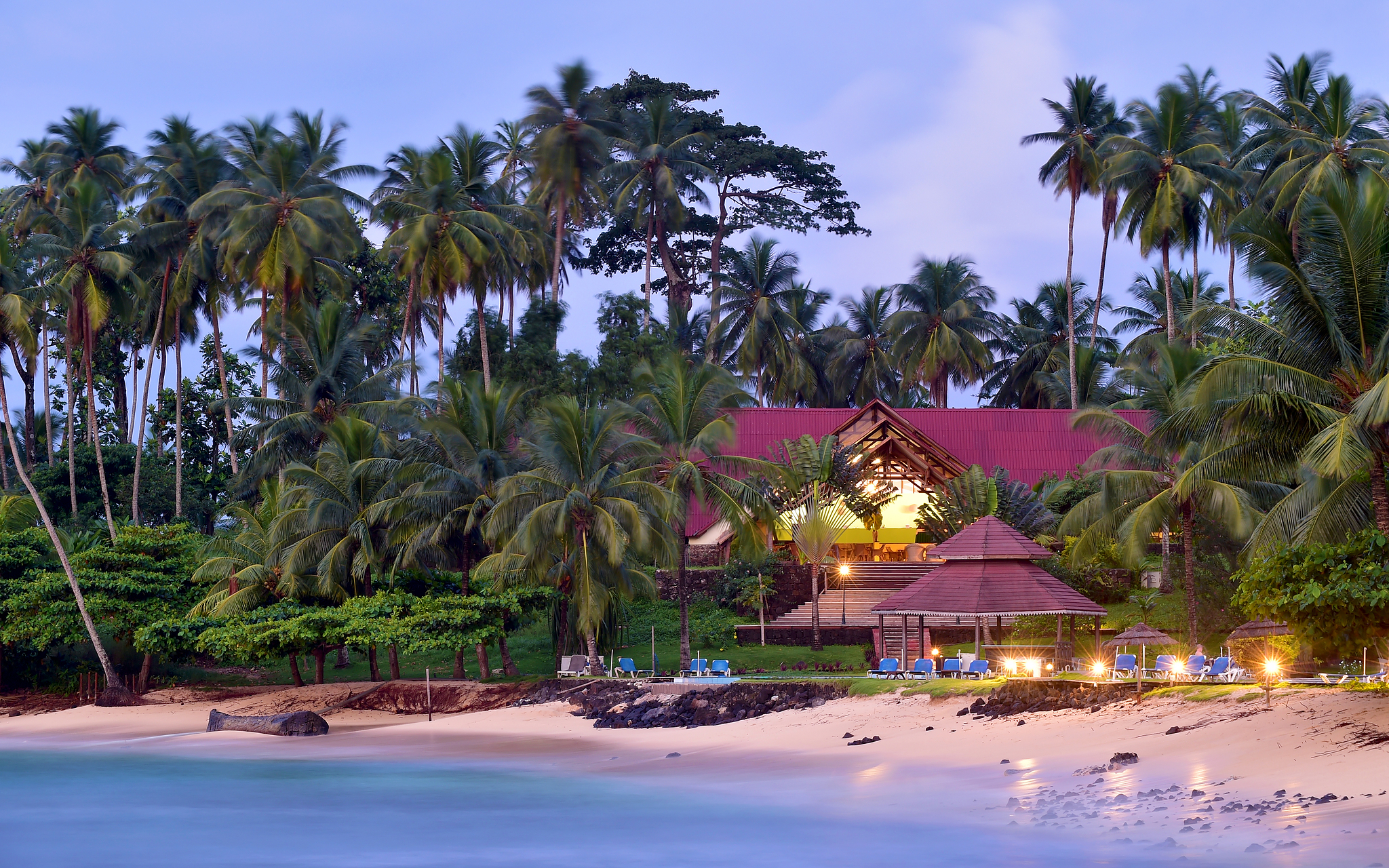 Plage et bâtiment avec transats et palmiers du Pestana Equador, hôtel sur l'île de Rolas, à São Tomé