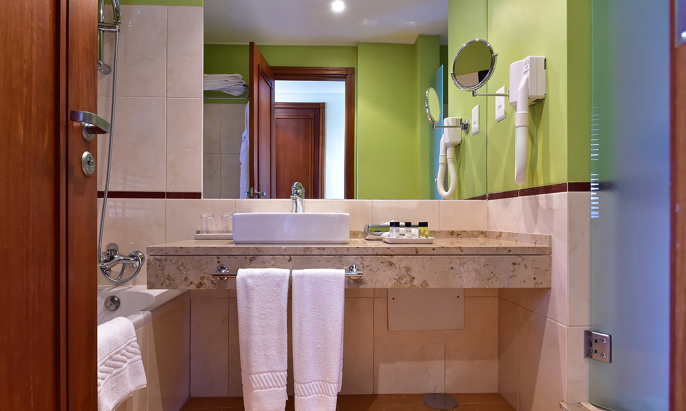 Le Quarto Standard du Pestana São Tomé a une salle de bain avec baignoire avec douche et une décoration en tons neutres