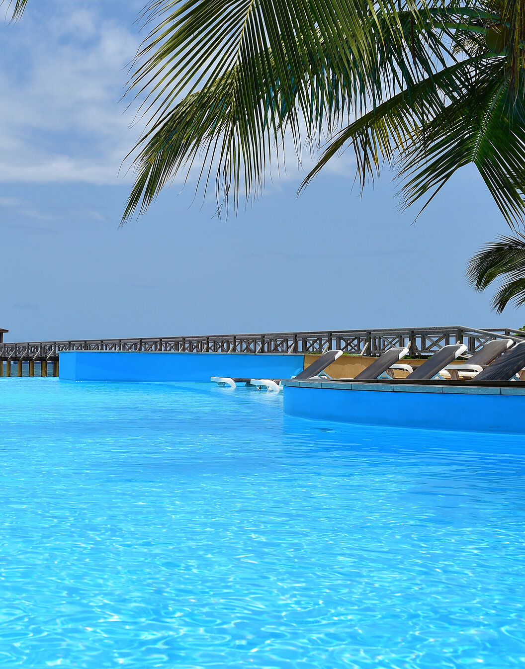 Vue paradisiaque de la piscine du Pestana São Tomé qui se fond avec la mer cristalline, un décor tropical idyllique