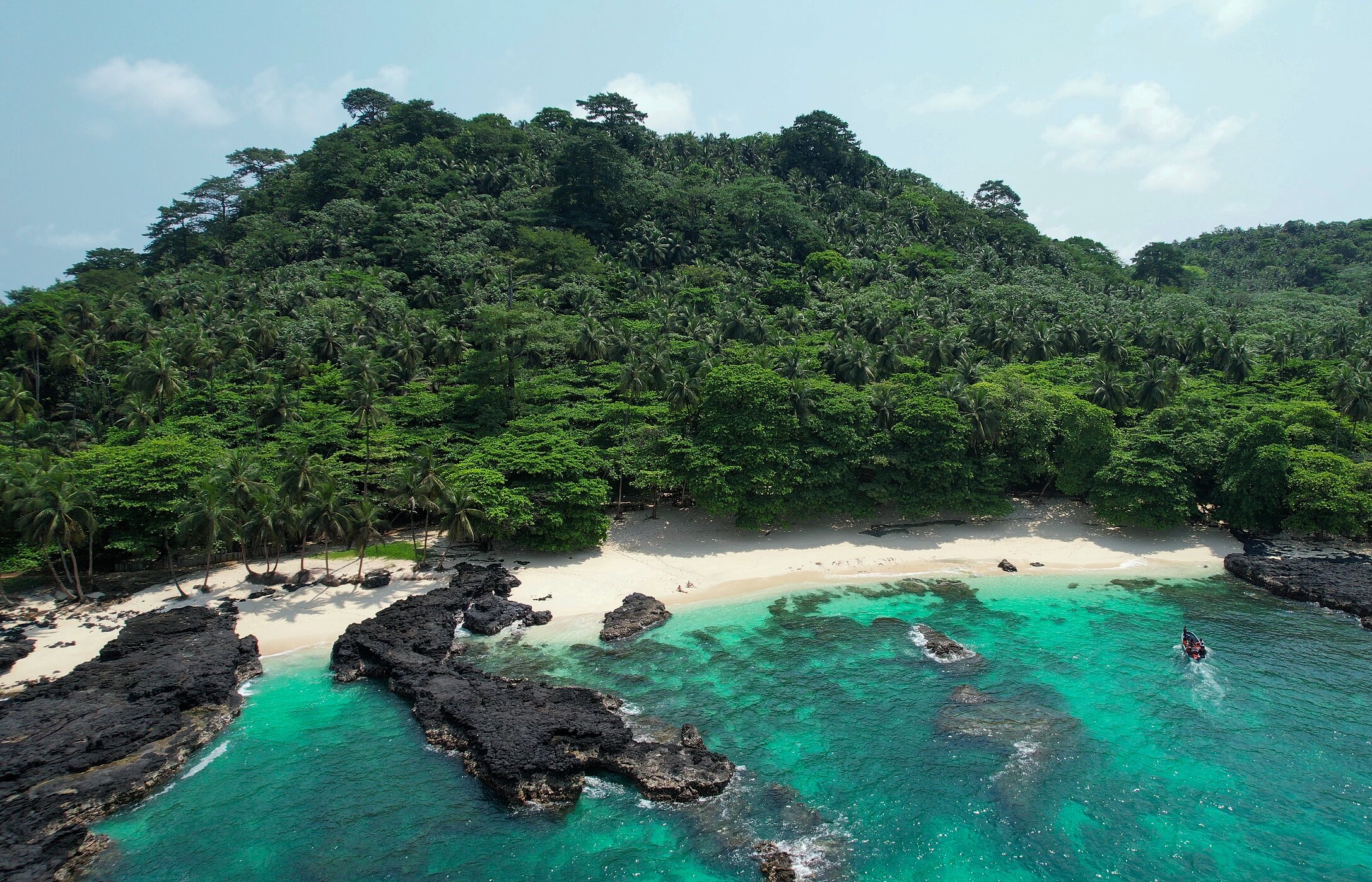 Praia Café, sur l'île de São Tomé, déserte, avec des rochers sur la plage et dans la mer, et un mur de végétation