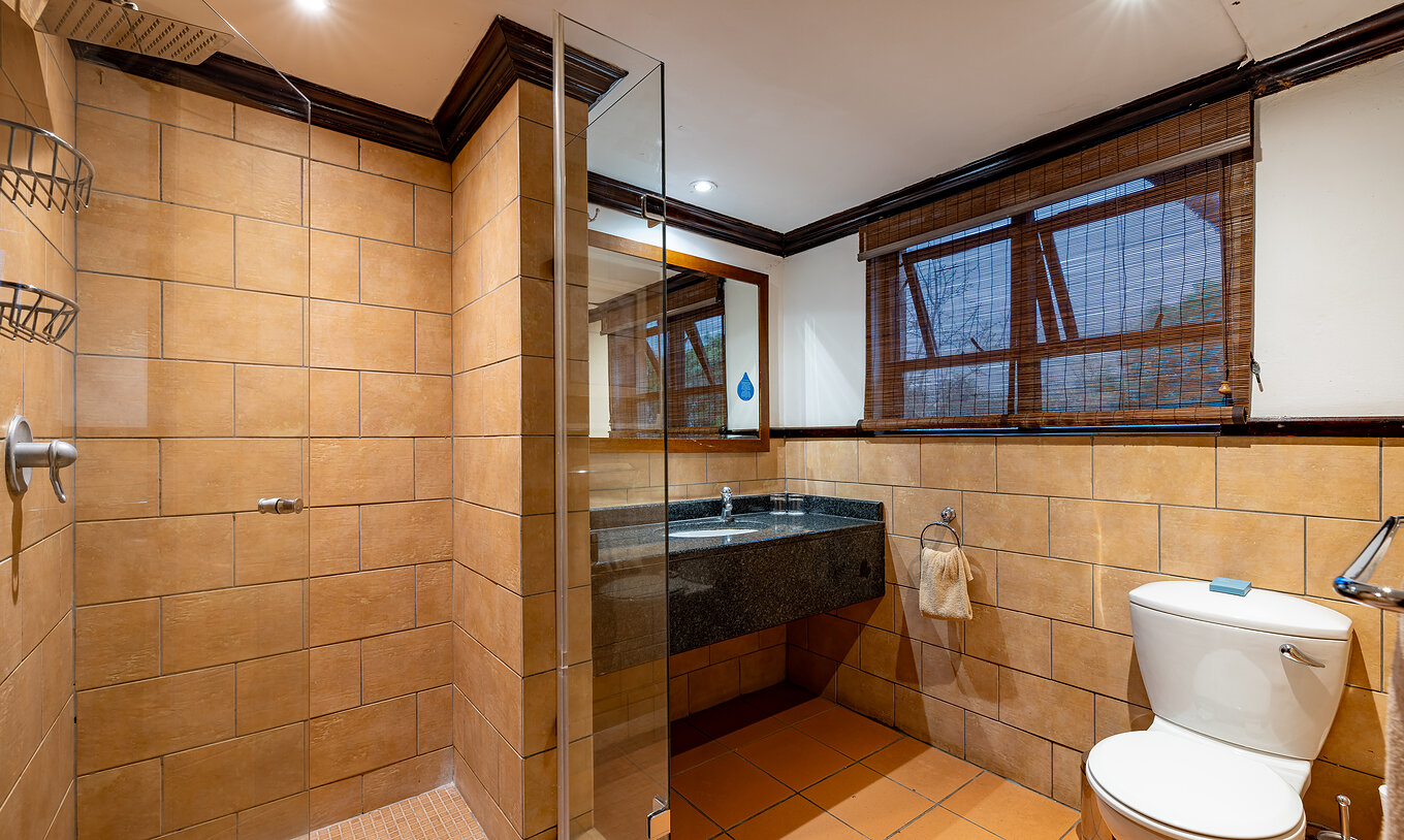 La Chambre Standard du Pestana Kruger Lodge a une salle de bain avec douche lavabo avec miroir et fenêtre avec moustiquaire