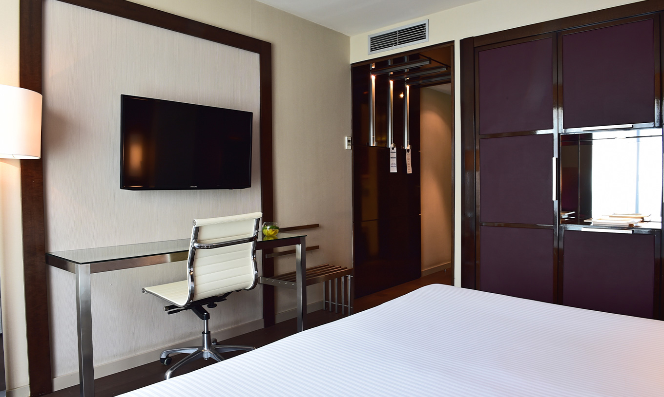 La chambre Premium du Pestana Arena Barcelona a une télévision au fond du lit et un placard violet pour rangement