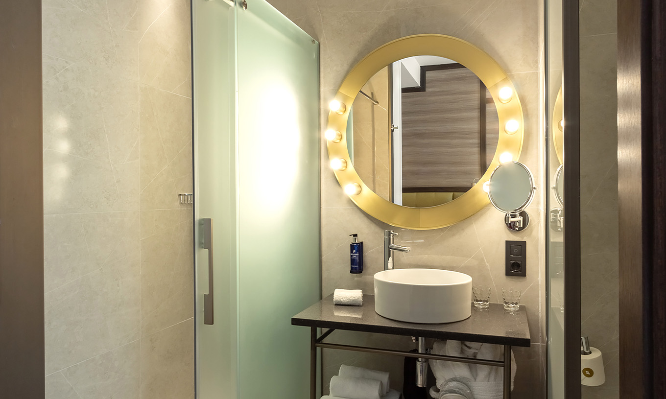 Le Deluxe Grand avec Vue du Pestana CR7 Gran Vía Madrid a une salle de bain avec miroir, lavabo et portes en verre