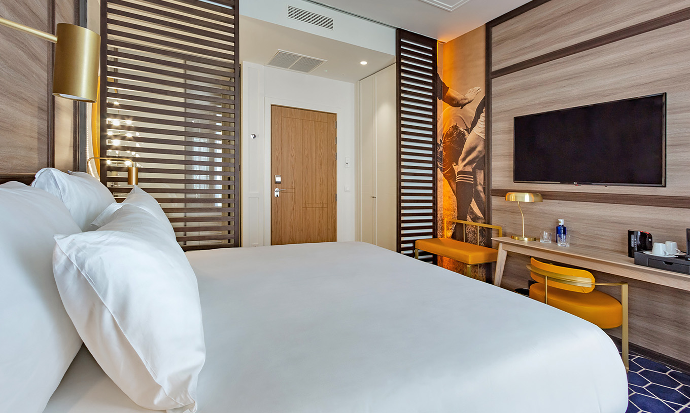 Le Premium du Pestana CR7 Gran Vía Madrid a un lit double, un bureau avec chaise et lampe, un banc et une télévision