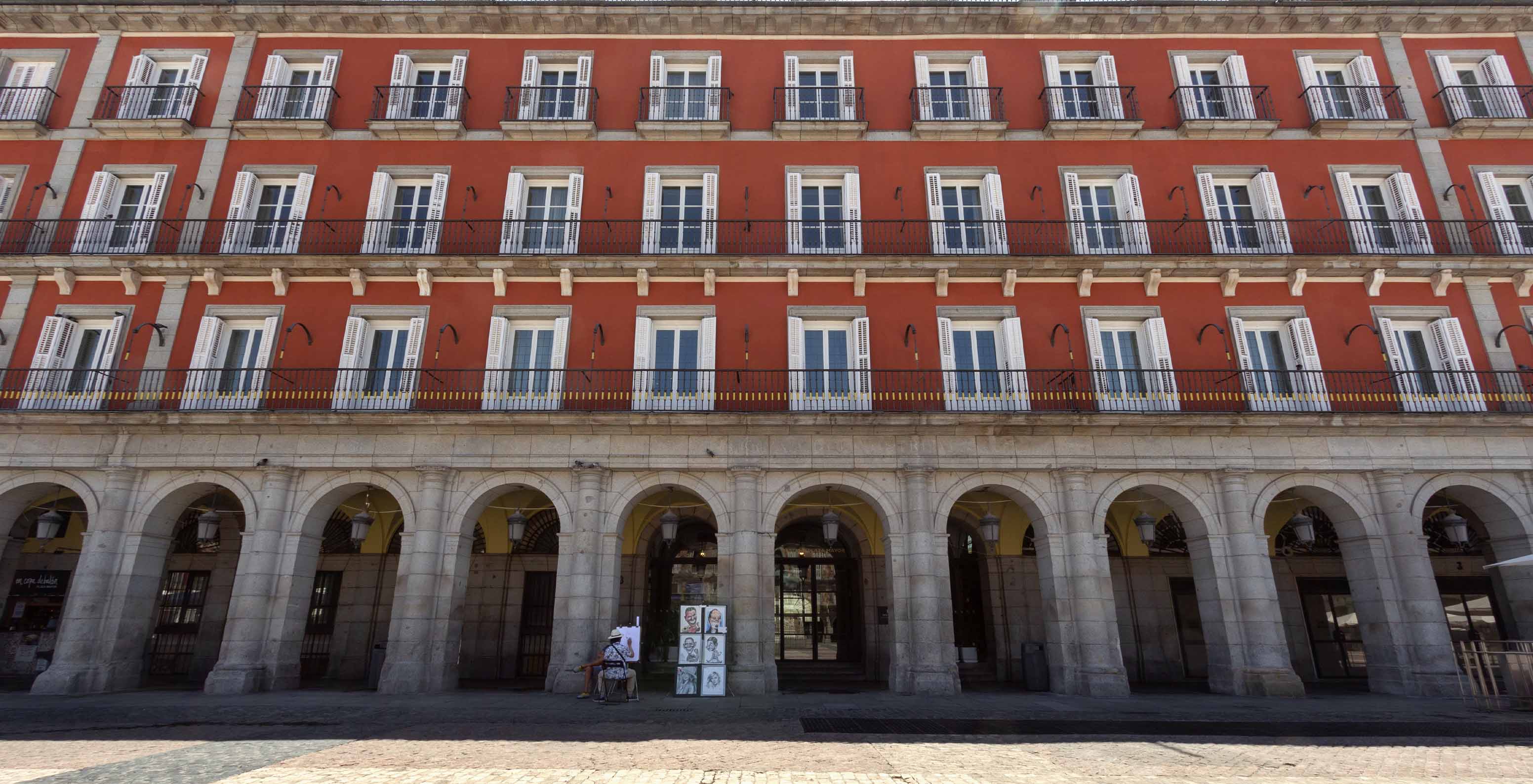 Vue de la façade du bâtiment du Pestana Collection Plaza Mayor, pendant la journée, peint en rouge avec plusieurs fenêtres
