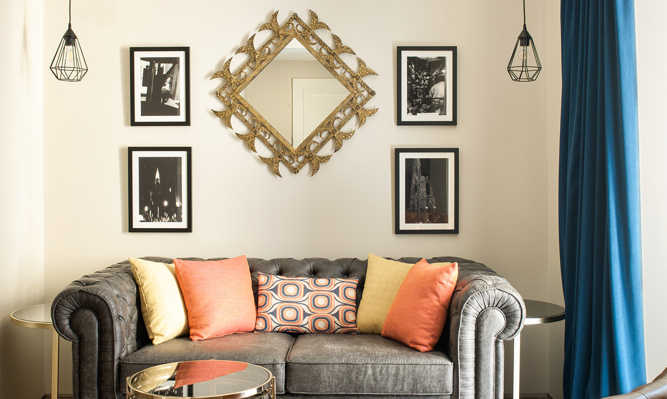 Le Deluxe Grand Plaza Mayor du Pestana Plaza Mayor Madrid a un canapé deux places gris et des tableaux au mur