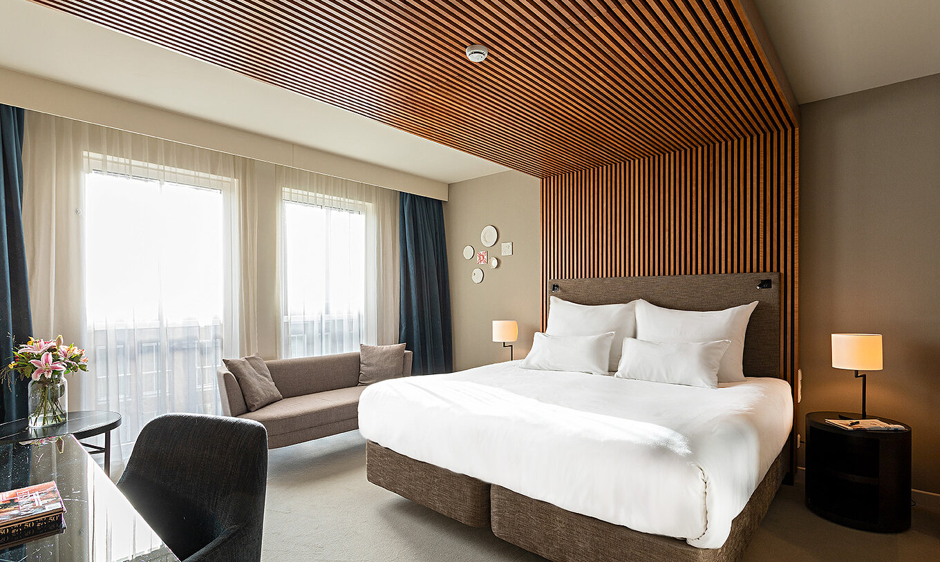 La chambre Executive du Pestana Amsterdam Riverside a un lit double, un canapé, et table de nuit avec lampe