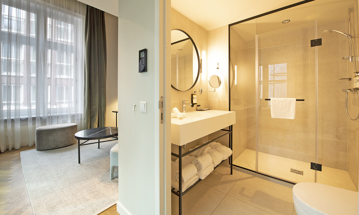 La Suite Mezzanine du Pestana Amsterdam Riverside a une salle de bain avec miroir, lavabo, serviettes et douche