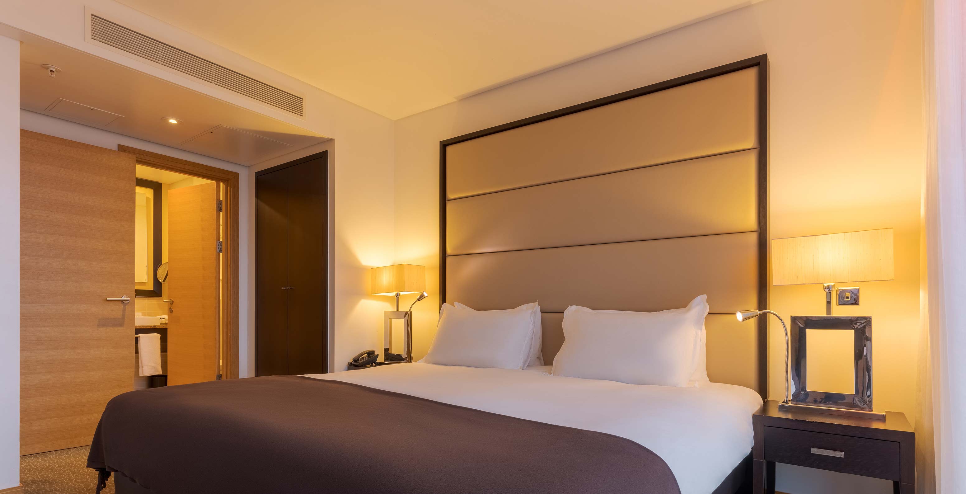 L’Executive One Bedroom Suite du Pestana Chelsea Bridge a un lit double et deux tables de nuit avec lampes