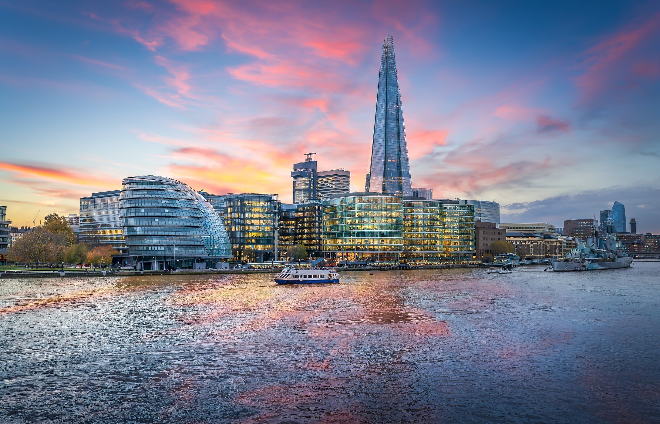 Vue panoramique de The Shard au coucher du soleil, avec un bateau naviguant sur la Tamise à Londres, Royaume-Uni.