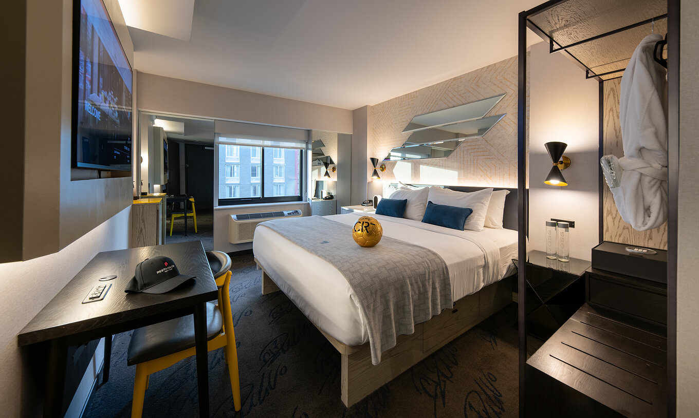 Le Deluxe King Room du Pestana CR7 Times Square a un lit double, un bureau et une armoire