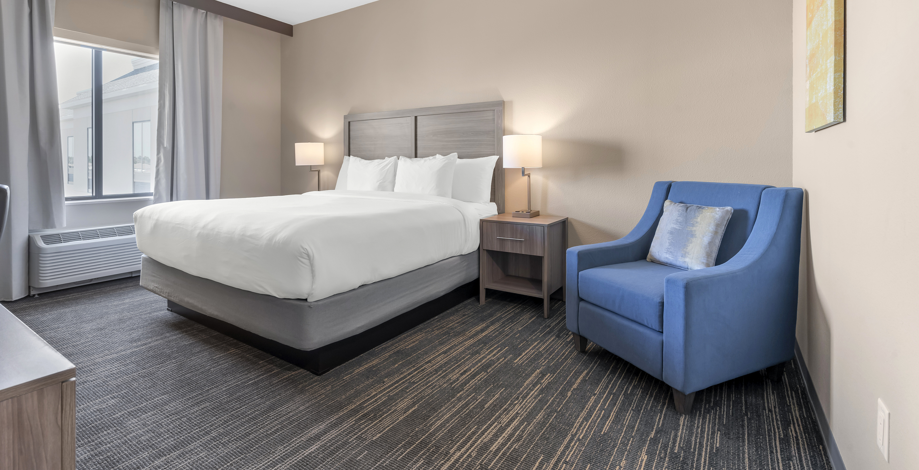 La Chambre King du Pestana Orlando Suites Lake Buena Vista a un lit double, table de chevet et fauteuil