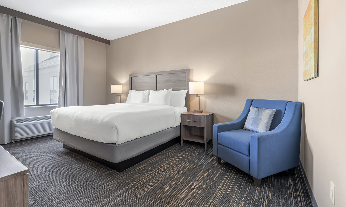 La Chambre King du Pestana Orlando Suites Lake Buena Vista a un lit double, table de chevet et fauteuil