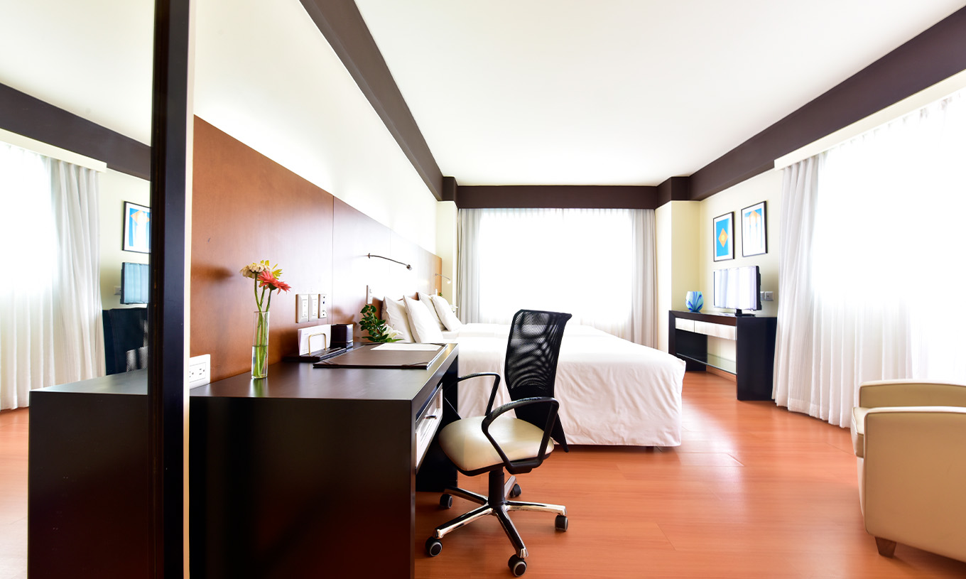 La Twin Junior Suite du Pestana Caracas a un lit double, un bureau avec une chaise ergonomique et une télévision