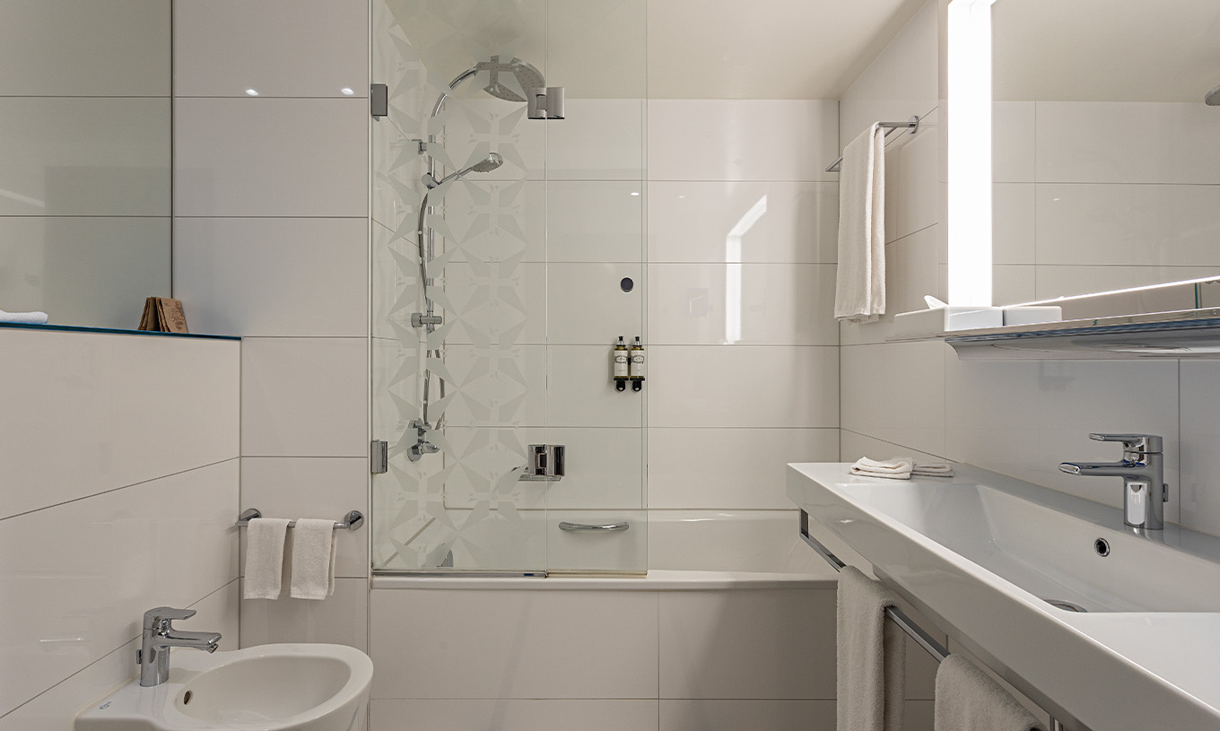 De Grand Deluxe Kamer van Pestana Berlin Tiergarten heeft badkamer met bad en douche en wastafel