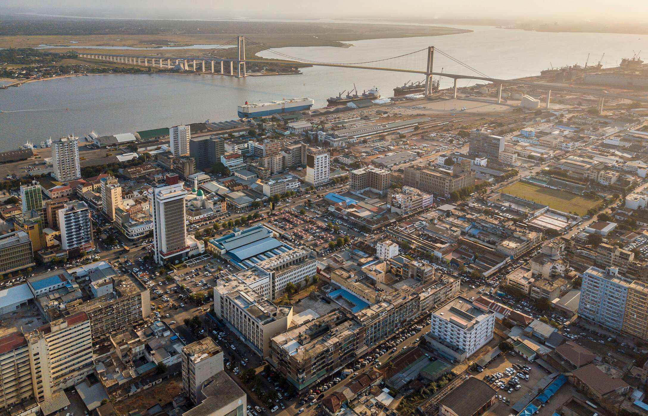 Luchtzicht op de stad Maputo, Mozambique, met verschillende gebouwen, auto's en een brug over een rivier.