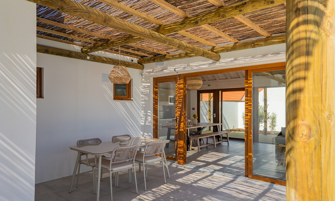 De Premium Villa bij Pestana Comporta Village Residences heeft een overdekte patio met een tafel die leidt naar het interieur