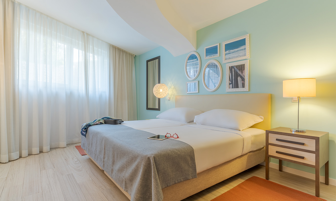 De Suite T1 met uitzicht op de tuin van Pestana Alvor Praia heeft twee bedden, nachtkastje met lamp, tapijt en schilderijen