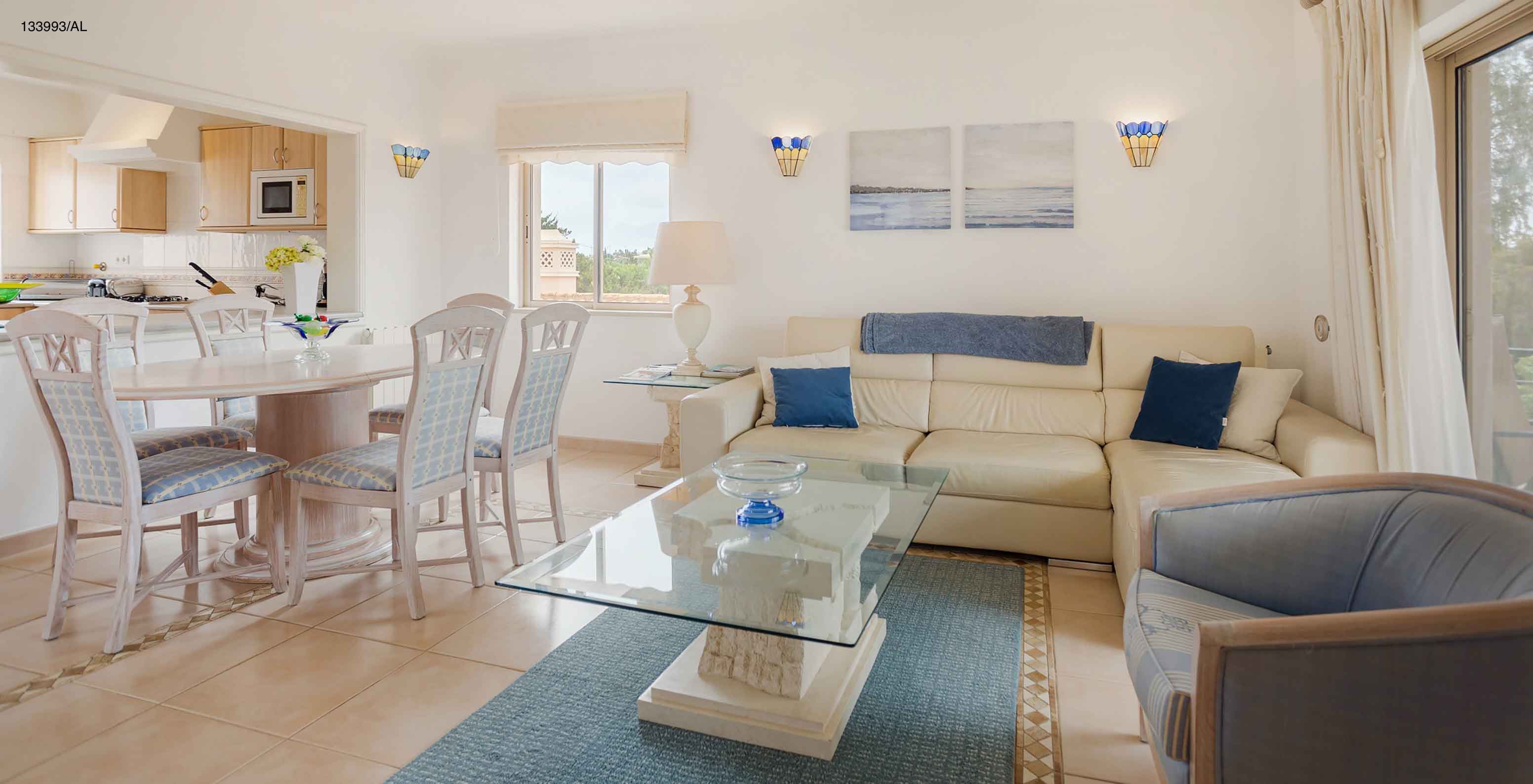 Het appartement Pestana Carvoeiro Golf T2 Superior heeft een woonkamer met een witte bank, een eettafel en zes stoelen