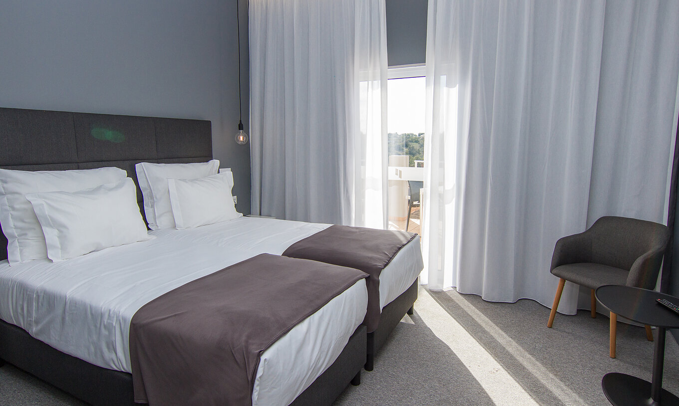 De Klassieke Kamer met Uitzicht op het Zwembad van Pestana Gramacho heeft twee eenpersoonsbedden, stoel en een raam