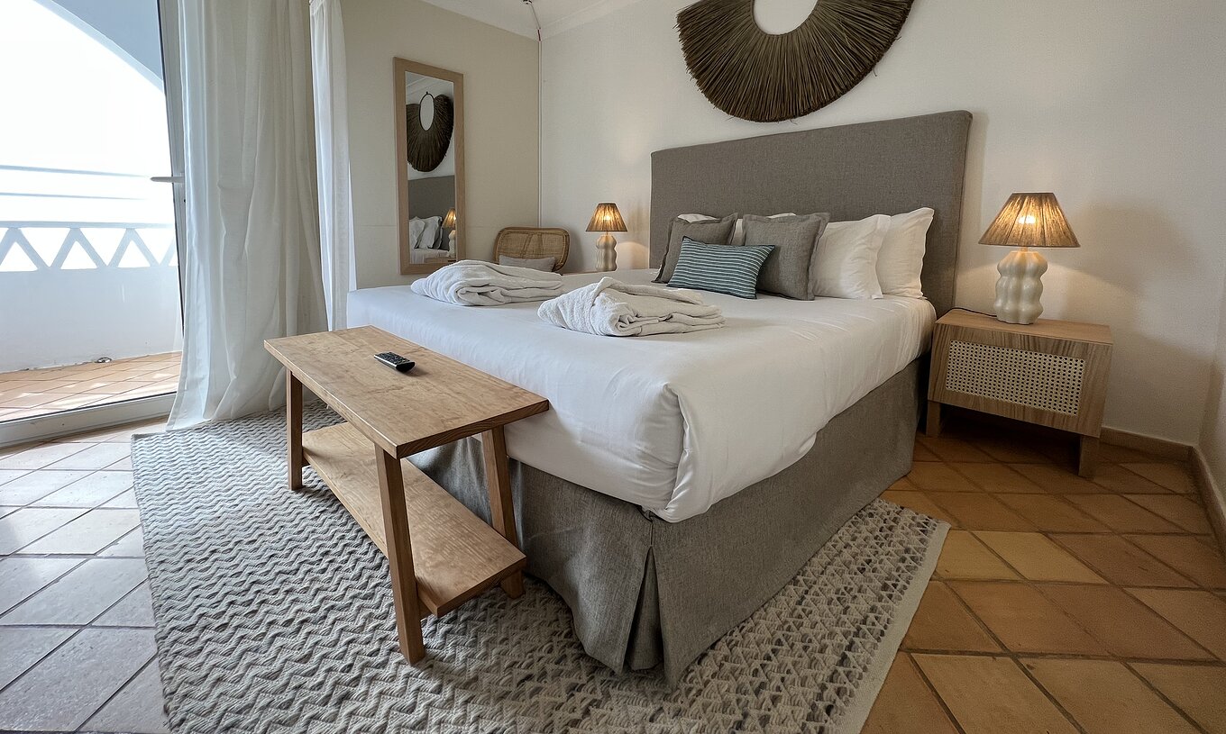 Het Appartement T2 Premium van Pestana Palm Gardens heeft een bed met twee badjassen, kussens en een raam met balkon