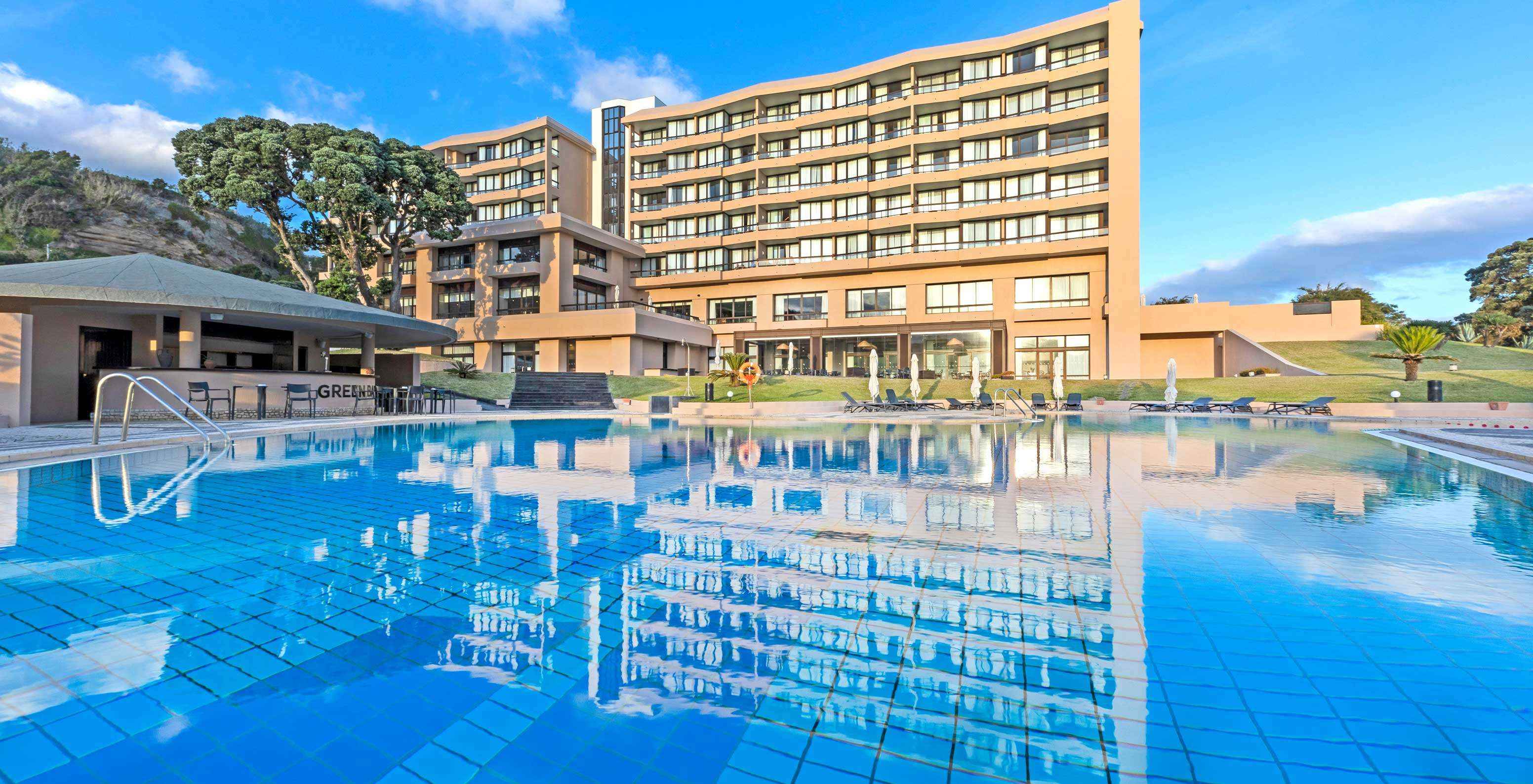 Buiten zwembad in het 4-sterrenhotel op het eiland São Miguel, met uitzicht op ligstoelen en het hoofdgebouw