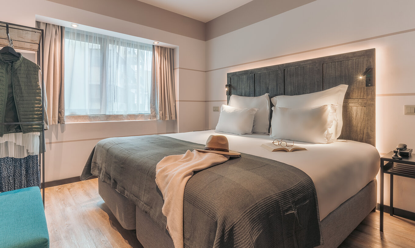 De Junior Suite Van Pestana Lisboa Vintage Heeft Een Tweepersoonsbed Met Deken Een Blauwe Bank Nachtkastje En Een Kast