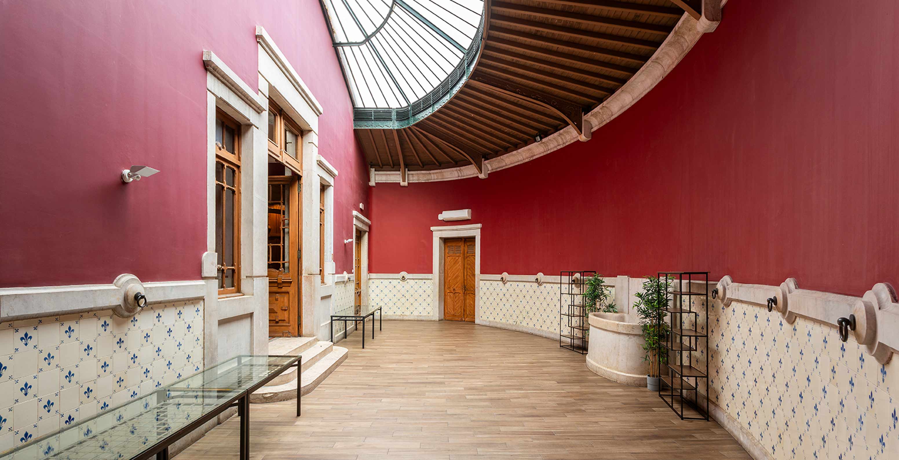 Pestana Palace Lisboa heeft een evenementenruimte met rode muren en blauw-witte tegels, versierd met planten