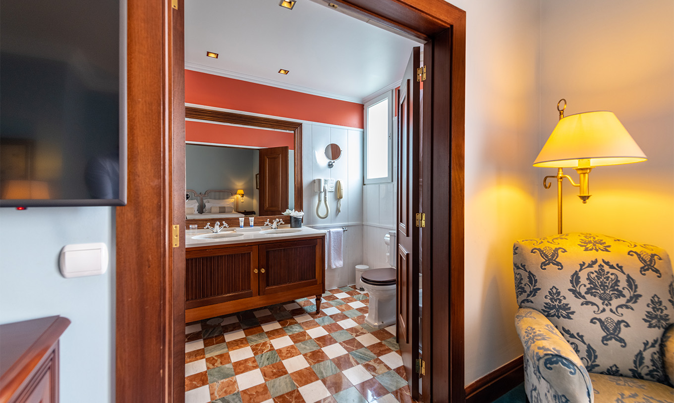 De Deluxe van Pestana Palace Lisboa heeft een badkamer met twee wastafels in een houten meubel, spiegel, toilet