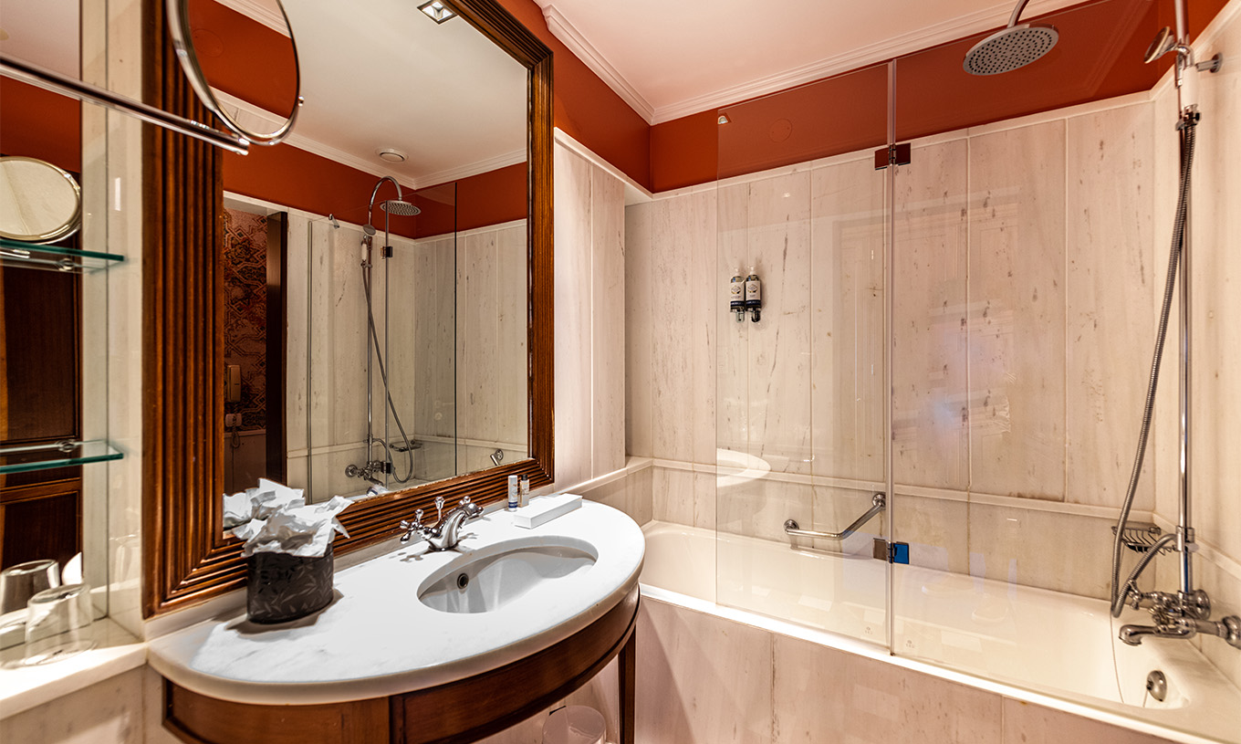 De Premium Garden van Pestana Palace Lisboa heeft een badkamer met ligbad en een wastafel in marmer en hout en spiegel