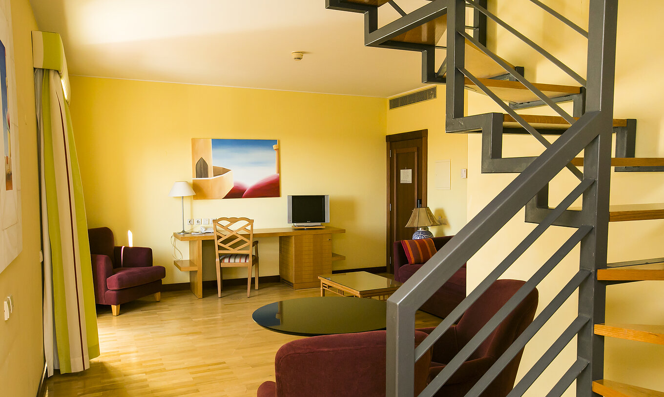De Deluxe Mezzanine Suite van Pestana Sintra Golf heeft een kamer met bank, fauteuils, televisie en schilderij aan de muur
