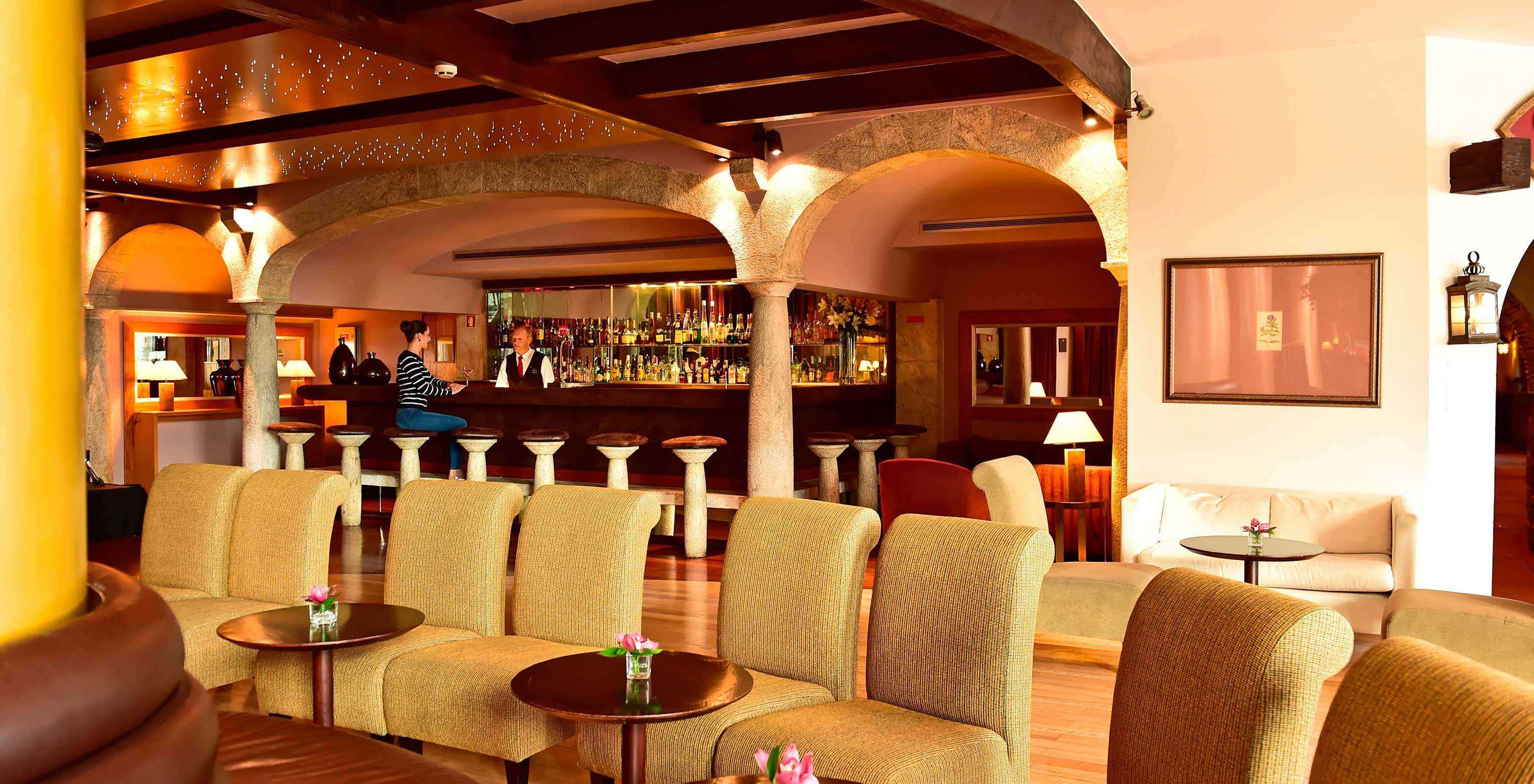 Pestana Carlton Madeira, een hotel in het centrum van Funchal aan zee, heeft een bar met verschillende dranken en stoelen