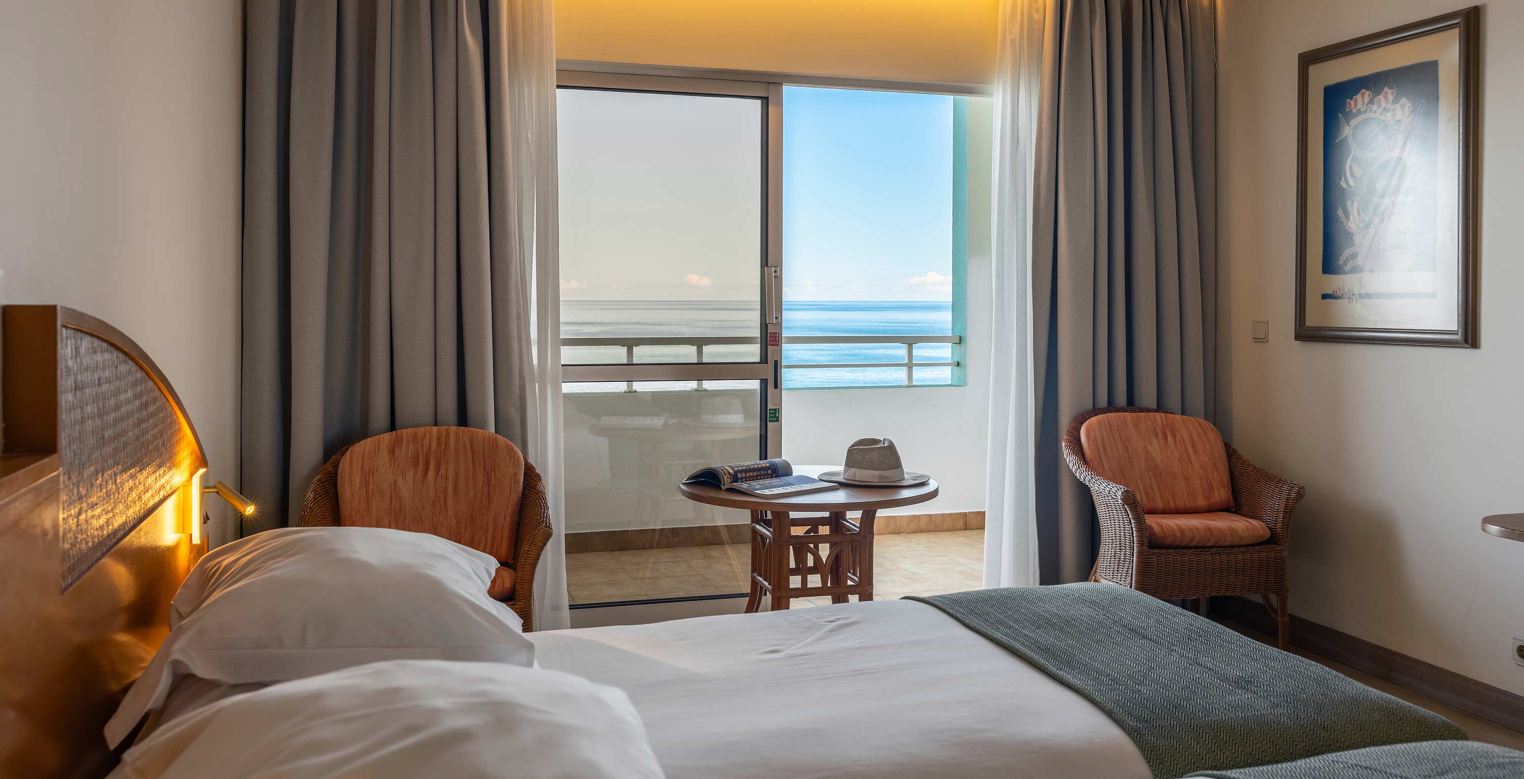 De Classic Sea View van het Pestana Ocean Bay All Inclusive heeft een tweepersoonsbed, twee stoelen en een balkon