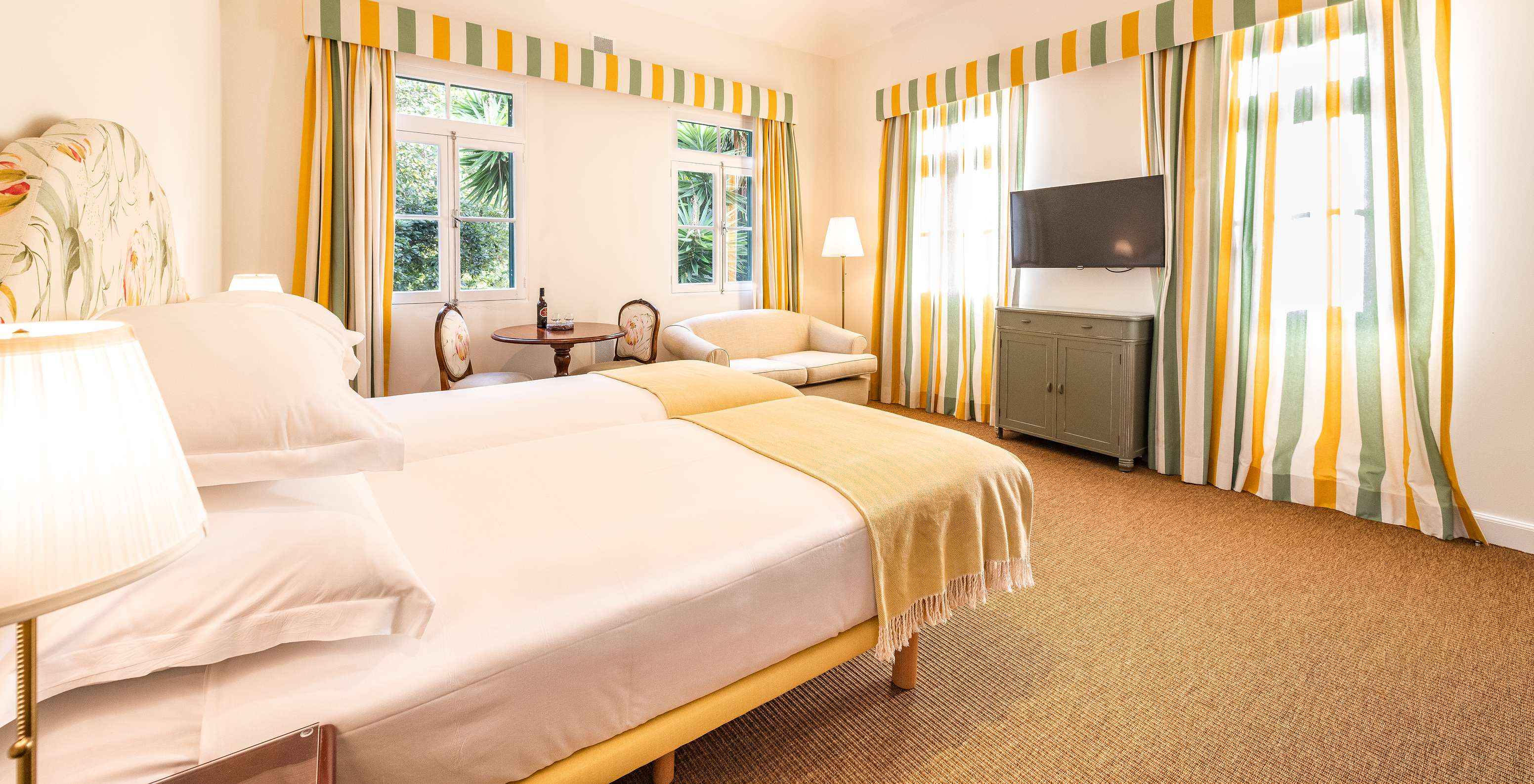 Pestana Quinta do Arco met Plattelandstoerisme op Madeira, met een lichte kamer met twee bedden, gestreepte gordijnen, een sofa en een tafel bij het raam