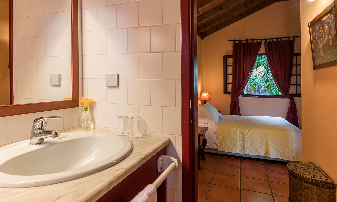 De Villas van Pestana Quinta do Arco hebben een badkamer met wastafel en de deur open naar de kamer met tweepersoonsbed