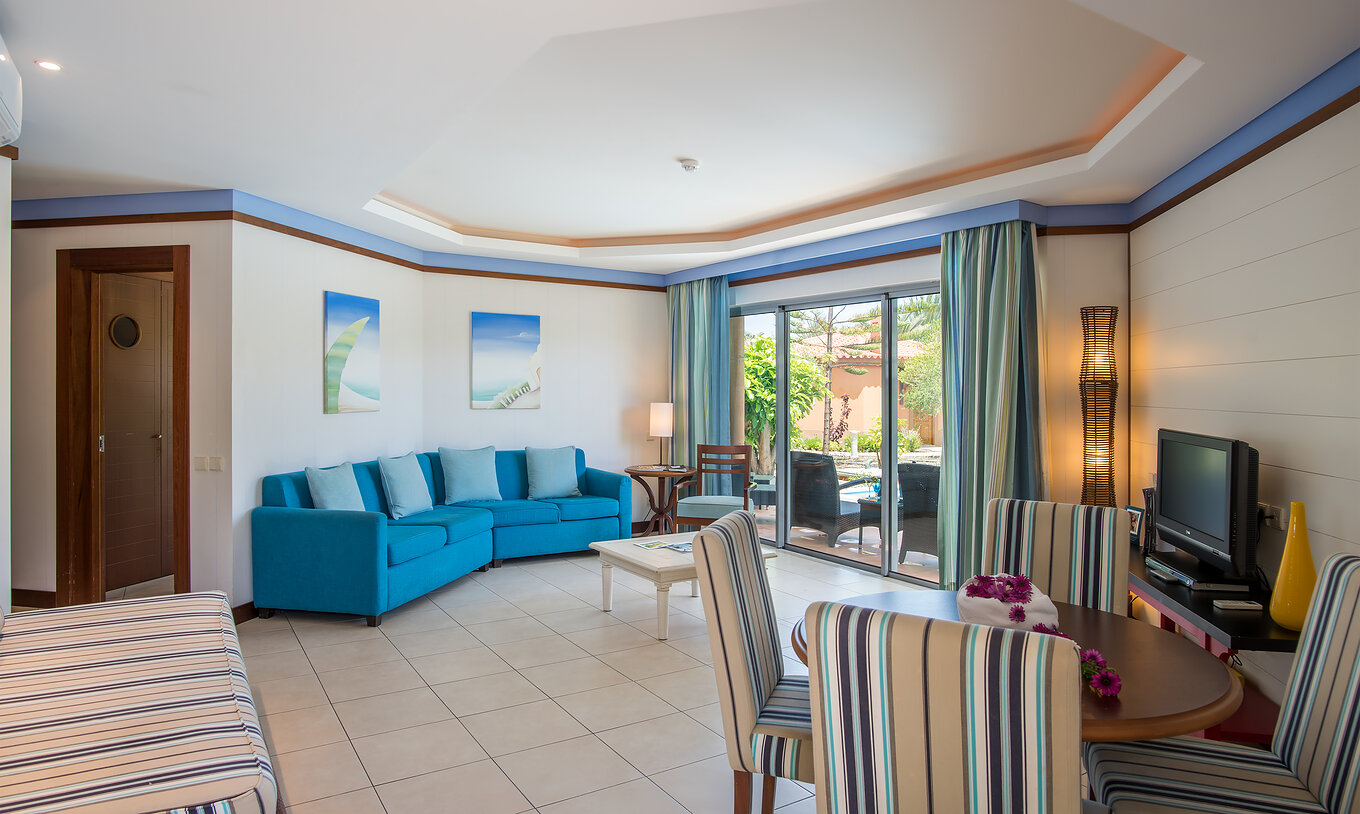 De Pool Villa van Pestana Porto Santo All Inclusive heeft een woonkamer met raam tafel stoelen bank en een televisie