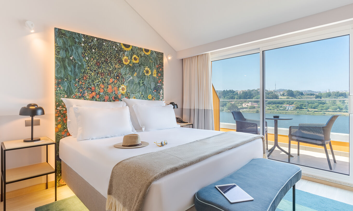 De Junior Suite van Pestana Douro Riverside heeft een tweepersoonsbed, nachtkastje met lamp en balkon met uitzicht
