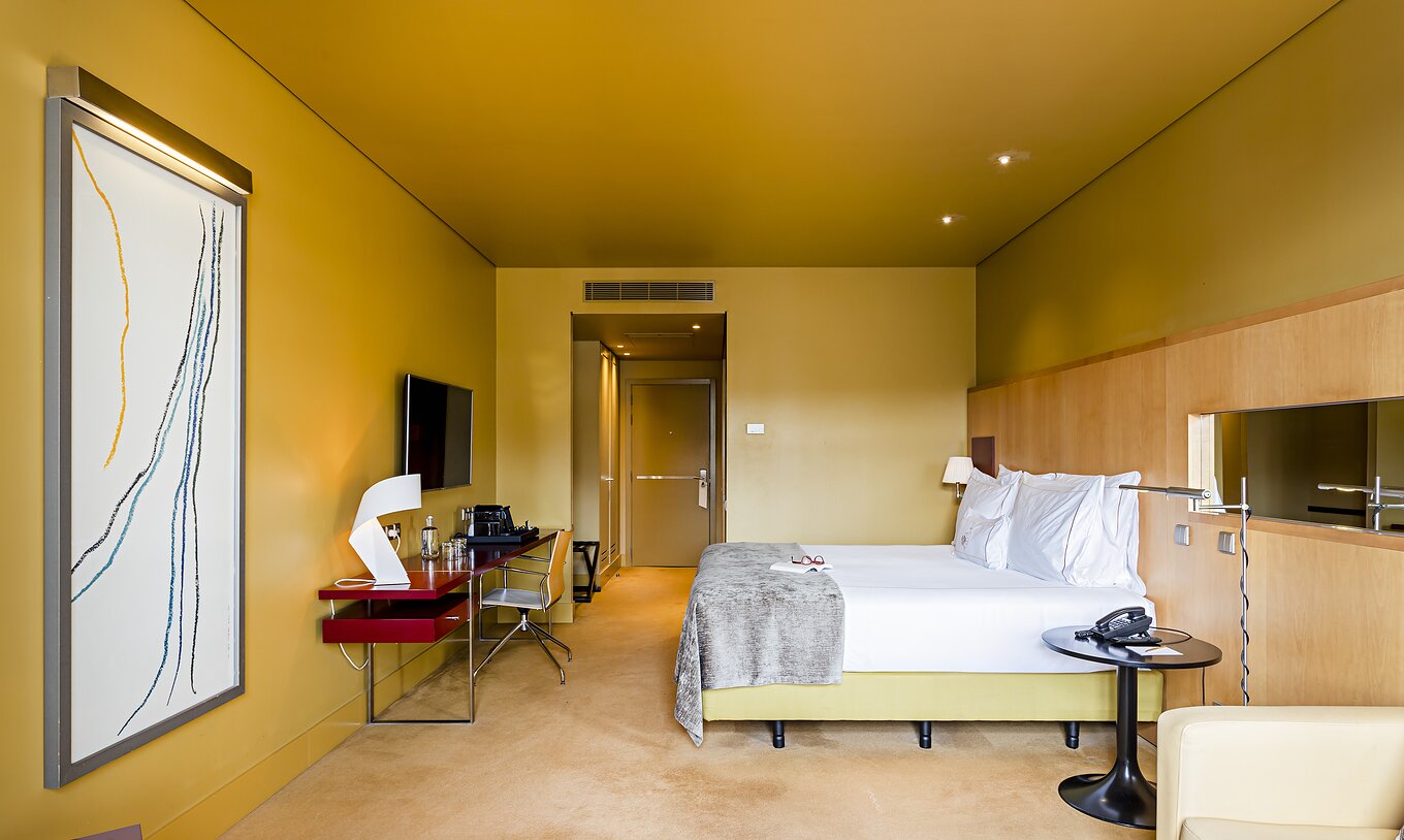 De Superior kamer van Pestana Palácio do Freixo heeft een tweepersoonsbed met een grijze sprei en een bureau