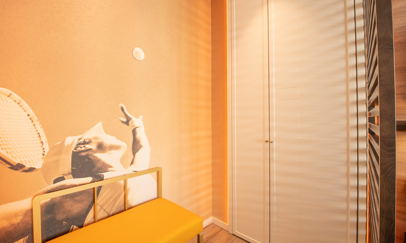 De Legend Room van Pestana CR7 Gran Vía Madrid heeft een kast, een bank en een foto van een tennisser als behang